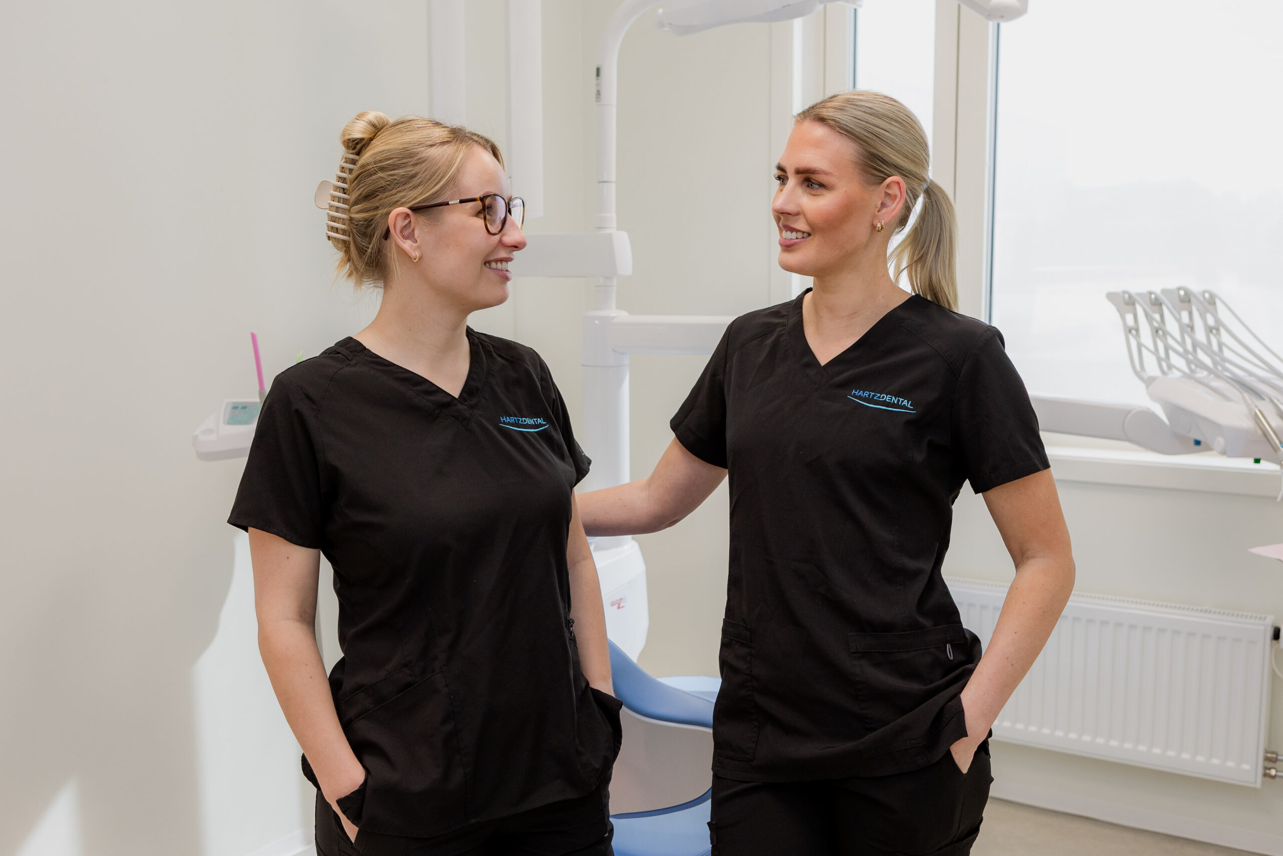 To smilende tannhelsearbeidere står sammen på klinikken